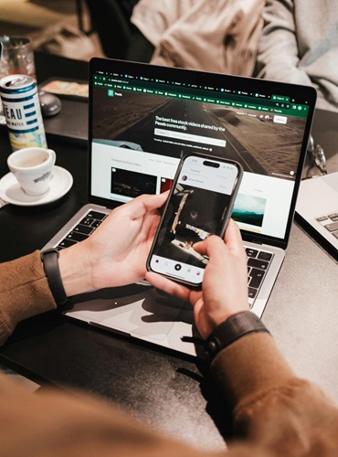 Person using a smartphone and laptop simultaneously, showcasing multitasking in technology.